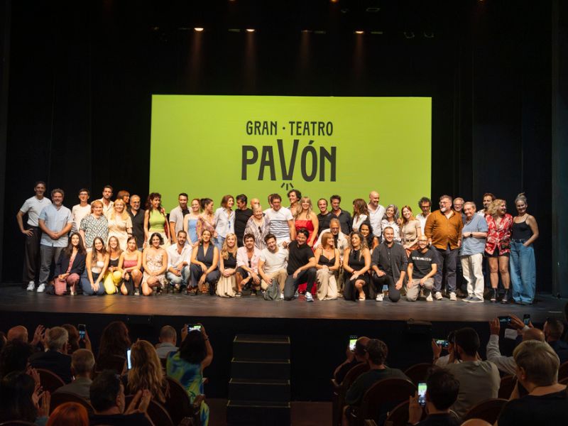 Foto de grupo sobre el escenario del Gran Teatro Pavón, con el equipo reunido frente a una pantalla amarilla con el nombre del teatro.