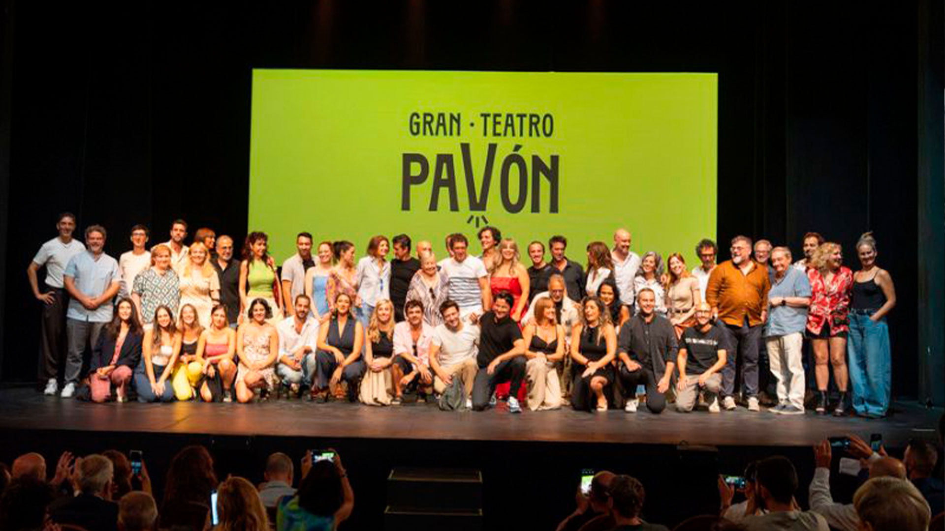 Foto de grupo sobre el escenario del Gran Teatro Pavón, con el equipo reunido frente a una pantalla amarilla con el nombre del teatro.