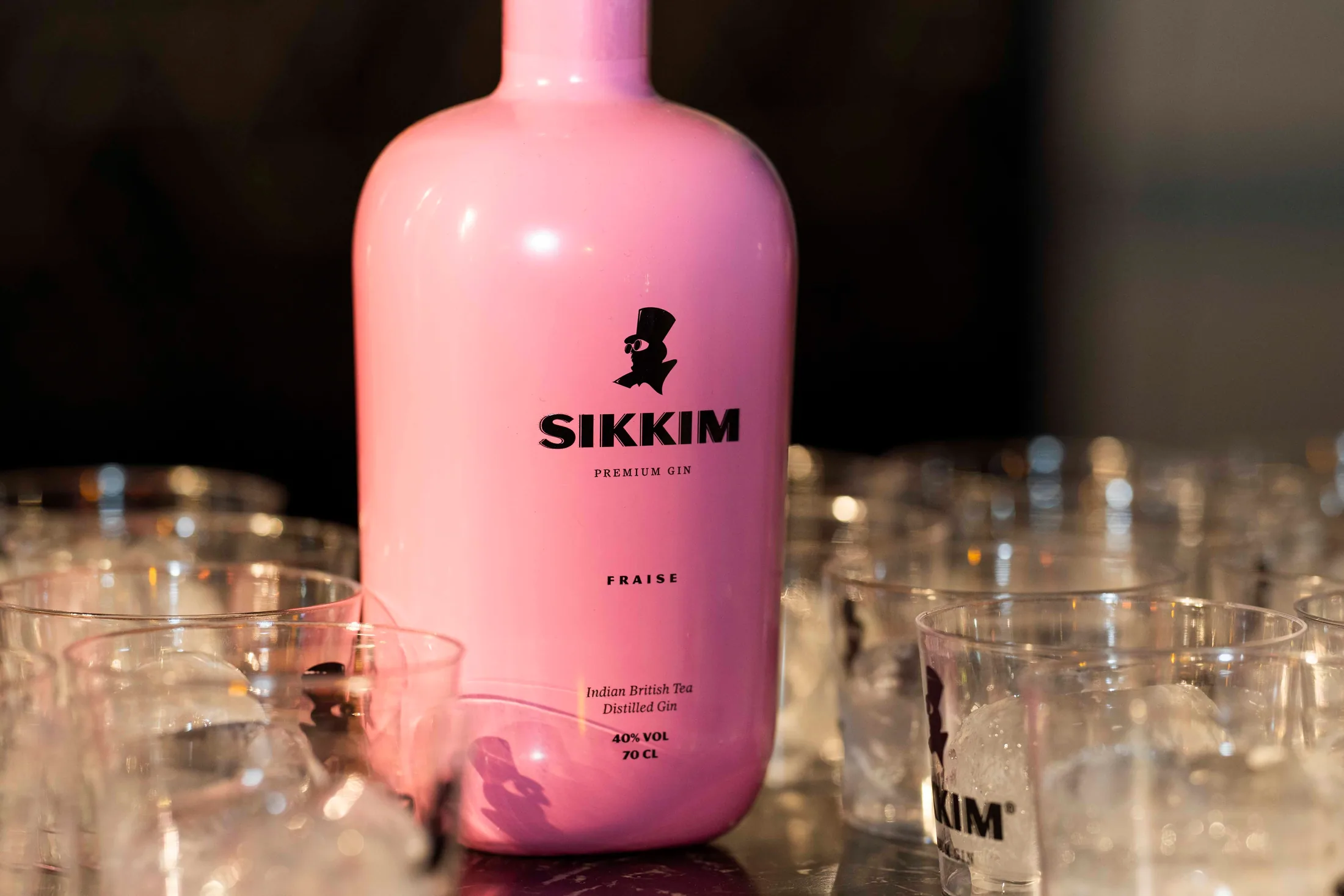 Botella rosa de Sikkim Gin rodeada de vasos en la barra del Ambigú